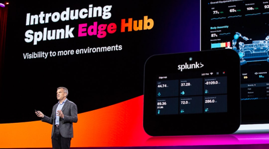 Eine Führungskraft von Splunk steht auf einer Bühne und stellt eine Neuerung in unserem Produktportfolio vor. Auf dem Bildschirm im Hintergrund sind Dashboards aus dem Produkt und der Text „Introducing Splunk Edge Hub“ zu sehen.