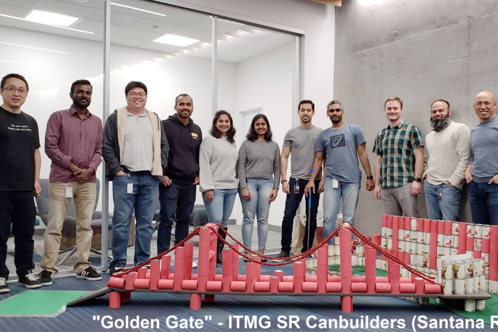 Les membres de notre équipe de solutions informatiques innovantes derrière une maquette du Golden Bridge en boîtes de conserve.