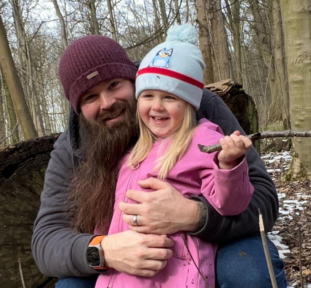 Ben Lovley, vétéran et Ingénieur commercial, porte sa fille dans ses bras lors d’une promenade dans la forêt.