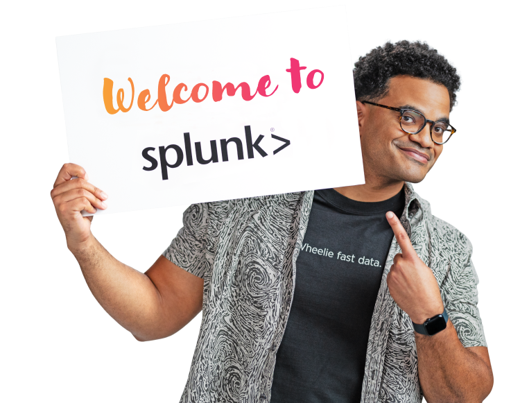 Ein Splunker zeigt auf eine Karte, die er in der Hand hält und auf der steht: „Welcome to Splunk“. Er trägt ein Splunk-T-Shirt mit der Aufschrift „Wheelie fast data.“.