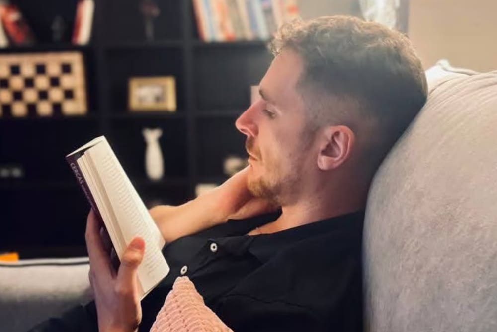  Oscar Gonzalez, Solutions Engineer at Splunk reads a book sitting on a couch.