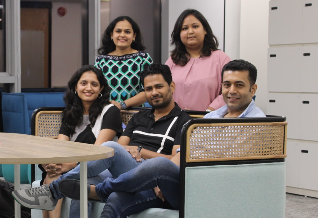 Five Splunkers smiling, three seated on a couch and two standing behind them in our Hyderabad office.