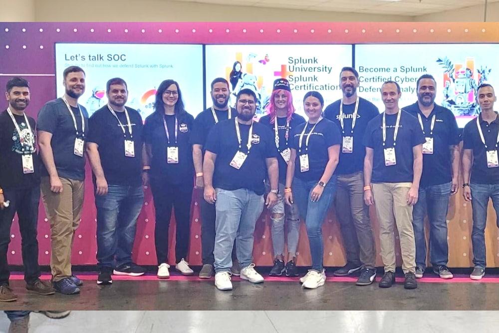 Team members standing together in front of a digital display at an event.