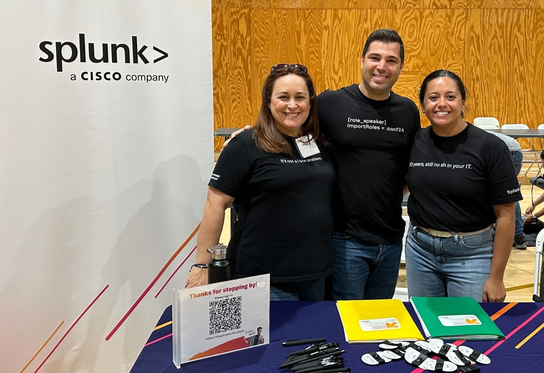 A Splunker attending a recruiting event. She is standing at a table filled with Splunk water bottles and t-shirts.