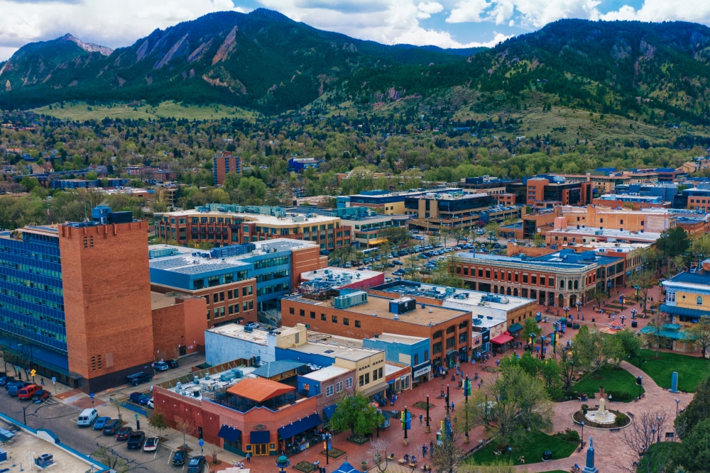 A cluster of brick and glass buildings with a park and pedestrian walkways at the base of a forested mountain range. Splunk has an office in Boulder, Colorado.