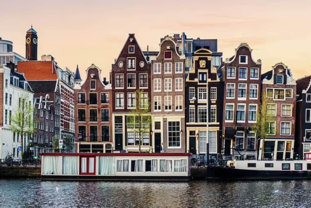Une série de six maisons à plusieurs étages devant un canal sur lequel se trouvent des péniches, à Amsterdam, où Splunk possède des bureaux.
