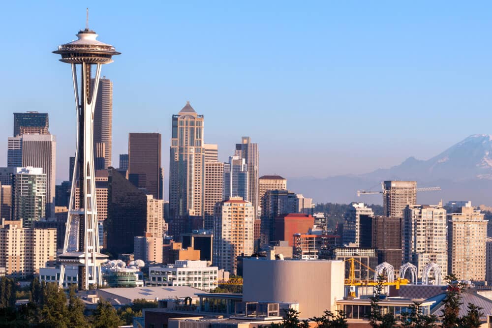 Standort von Splunks Büro in Seattle, Washington. Die Space Needle vor einer Gruppe von hohen Geschäftsgebäuden im Geschäftsviertel von Seattle. In der Ferne sieht man einen Berg.