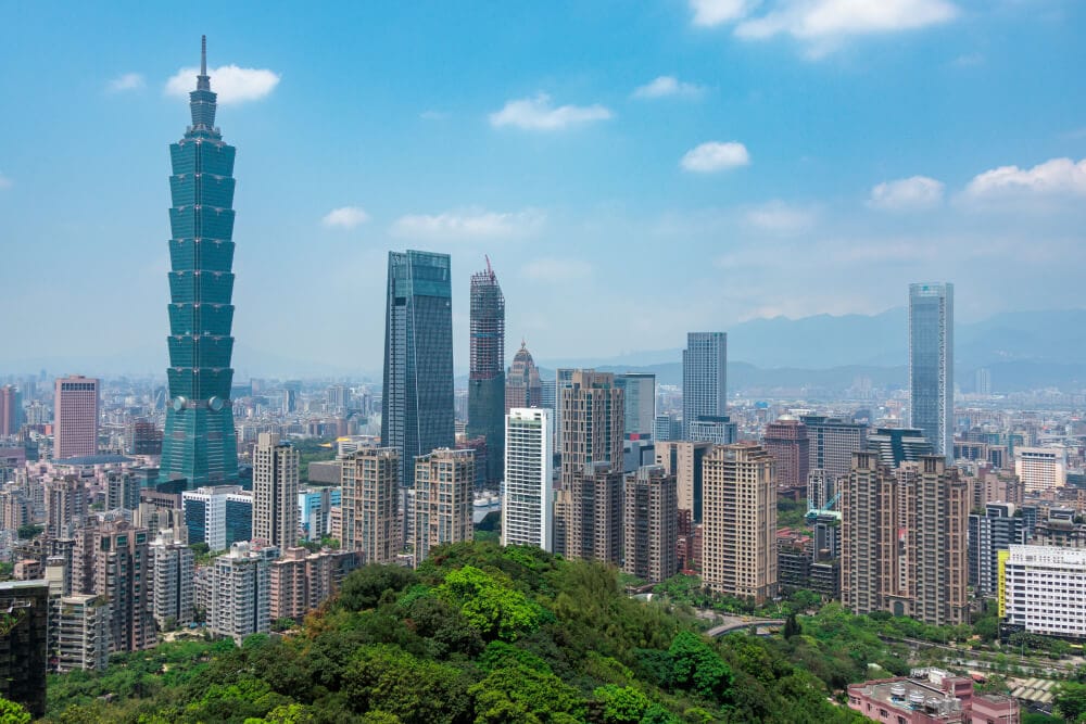 Standort von Splunks Büro in Taipeh, Taiwan. Ein blauer, chromfarben glitzernder Wolkenkratzer ragt über einem Rechteck mit üppiger grüner Vegetation, gesäumt von braunen Hochhäusern, auf.