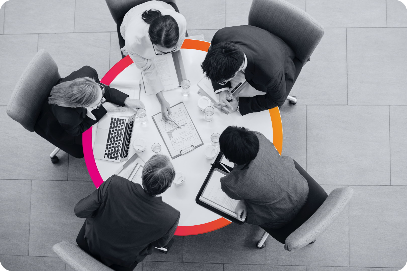 A bird's eye view of two seated people in businesswear huddled together looking at a tablet screen.