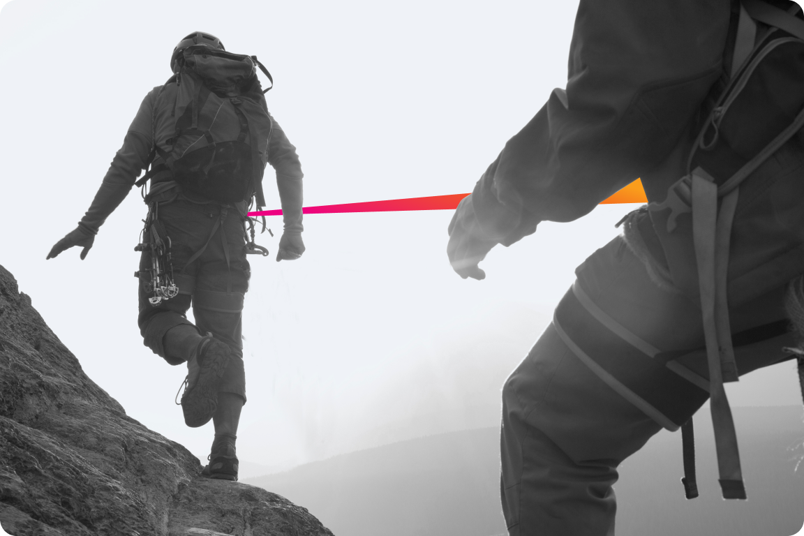 Two climbers connected by a rope climbing a mountain.