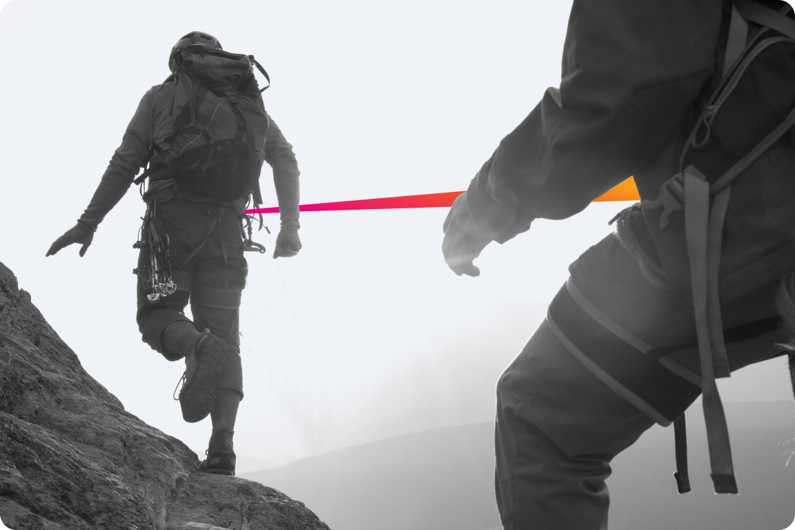 Two climbers attached by a taut rope climbing a mountain