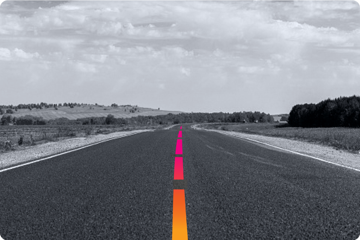 A black and white image of a empty piece of road with the center divider colored in gradient.