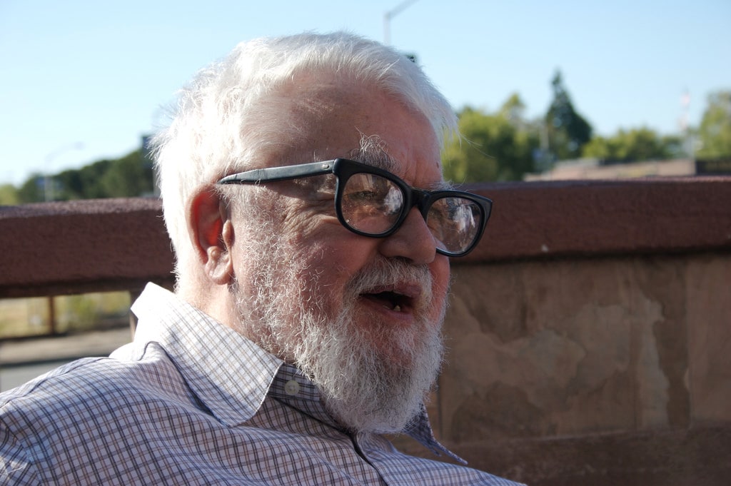 Color photo of an older John McCarthy looking to his left and smiling.